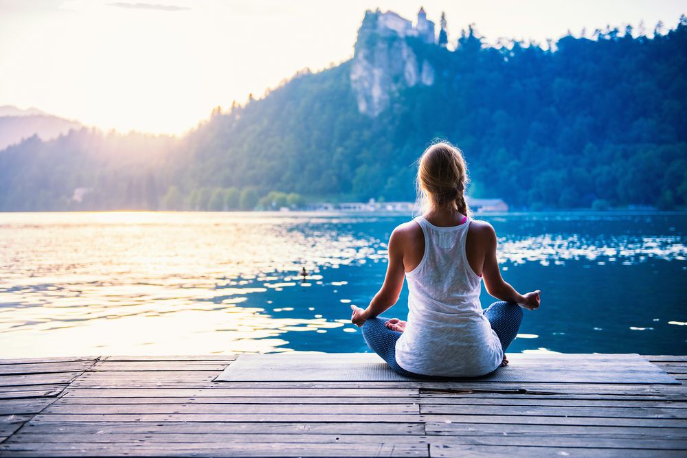 Woman meditating beside a lake
